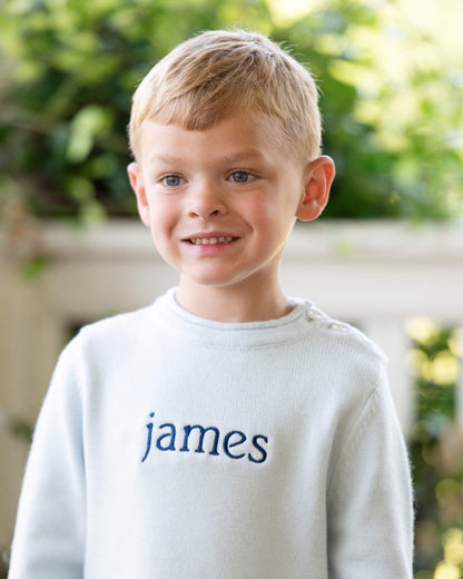 Young boy in blue sweater with name james embroidered on the center