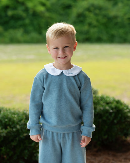 Young_boy_wearing_a_blue_sweater_with_a_white_collar_outdoors._1