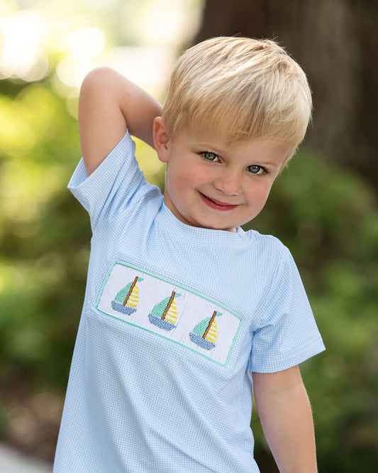 Young boy wearing a light blue shirt with sailboat design outdoors