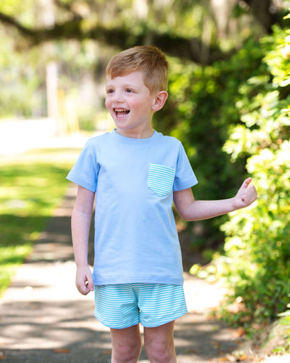 Young boy wearing a light blue t-shirt and striped shorts outdoors.