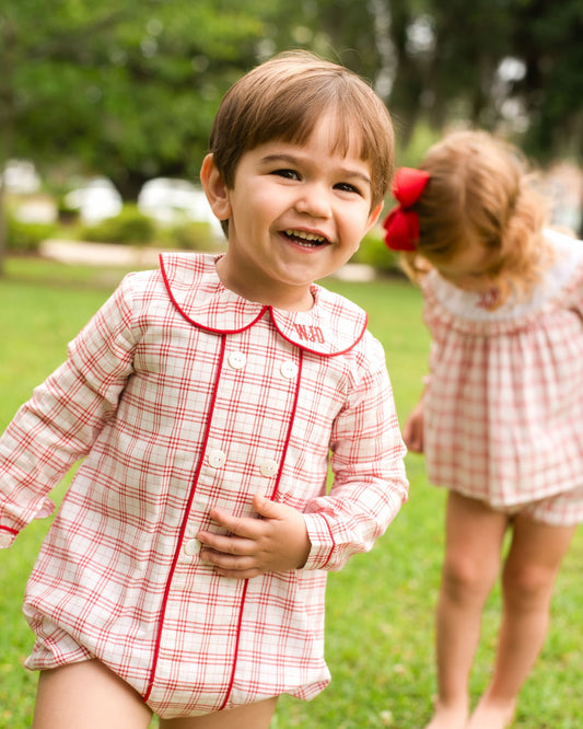 Young boy wearing a red plaid outfit smiling