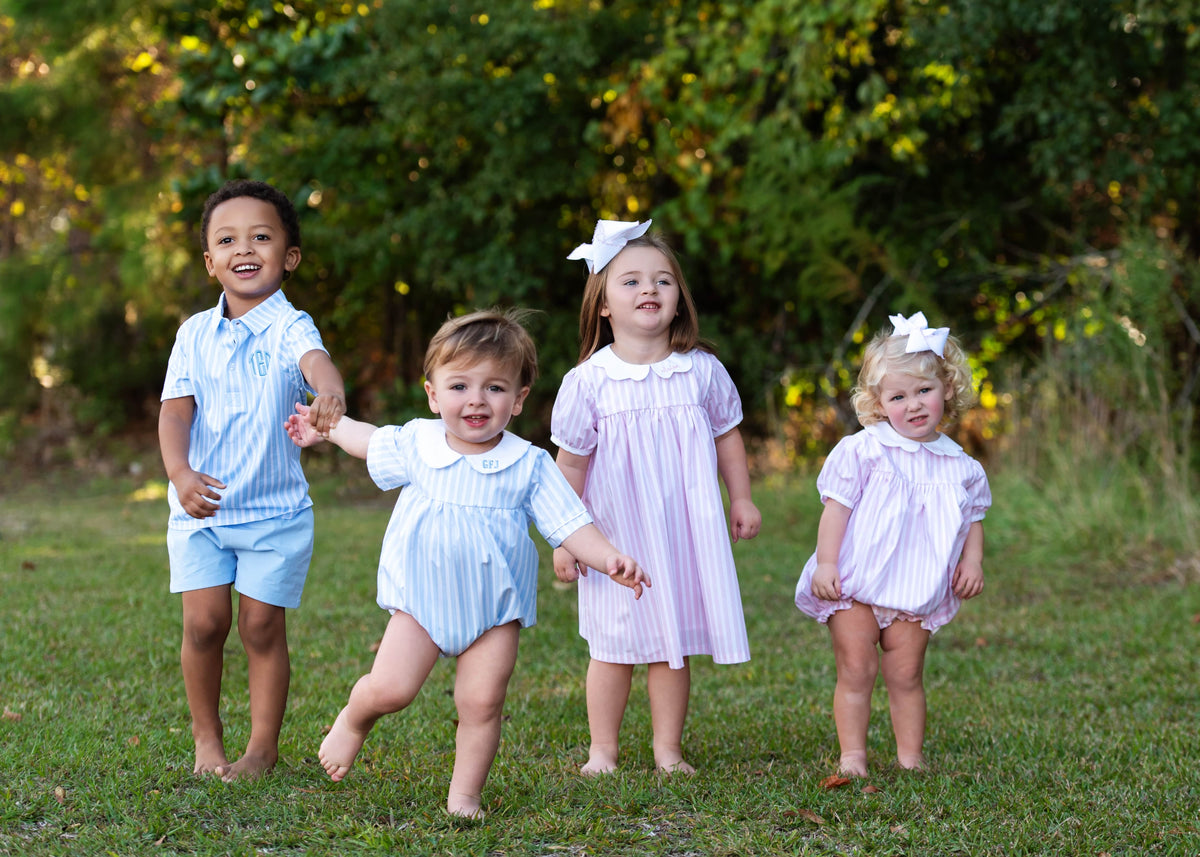 Young children playing outside wearing matching blue and pink striped outfits
