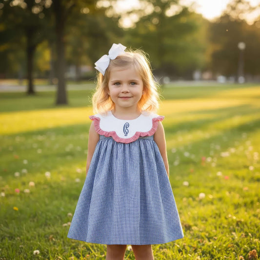 Young girl in a blue checkered dress with a white bow in a park