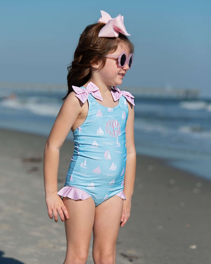 Young girl in a blue swimsuit with pink accents on a beach