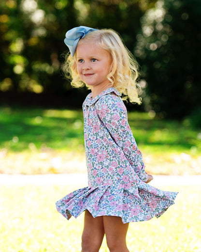 Young girl in a floral dress with a blue bow outdoors