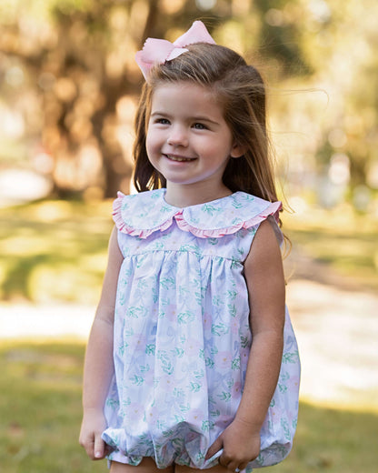 Young girl in a floral dress with a pink bow in a park setting