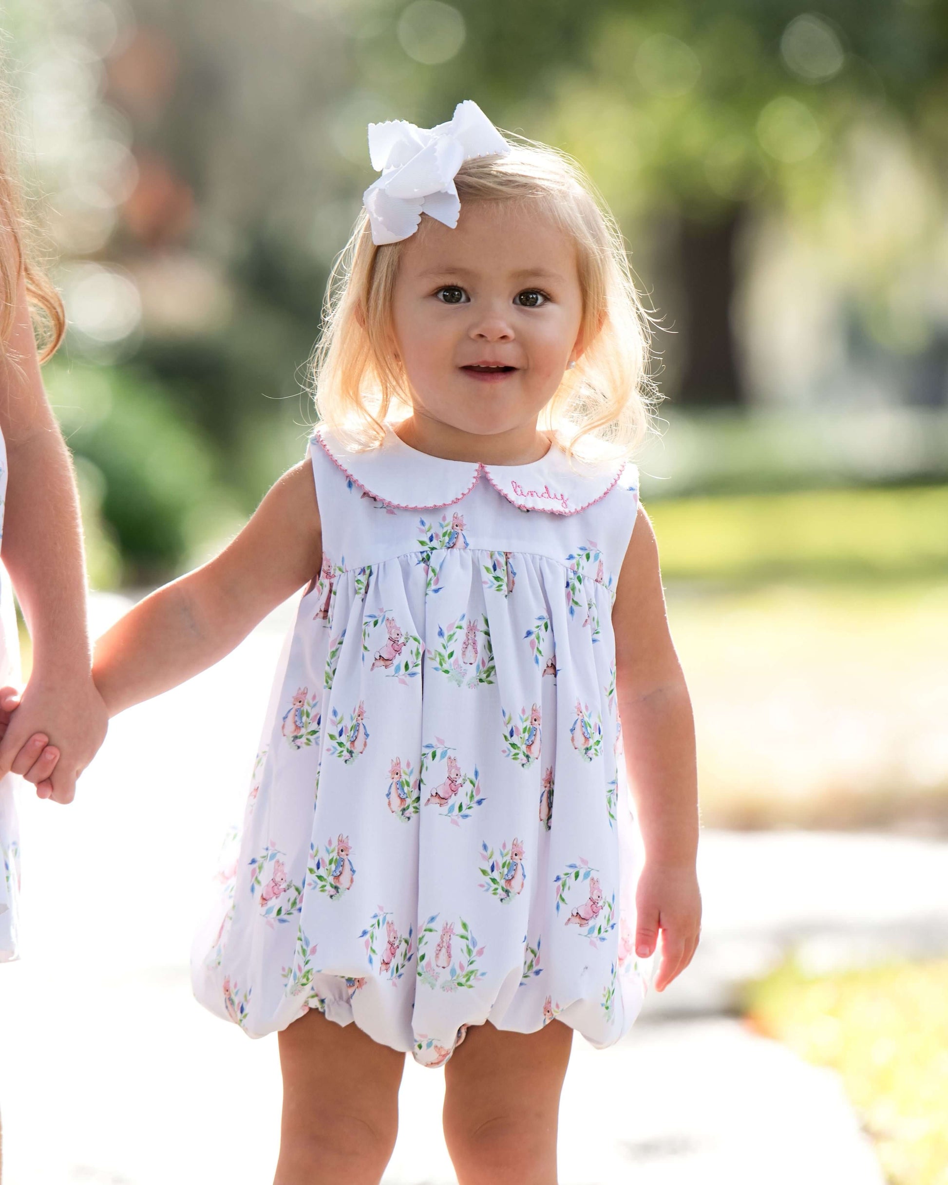 Young girl in a floral dress with a white bow in a park setting