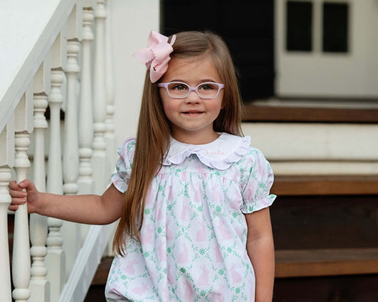 Young girl in a floral dress with glasses standing on a staircase