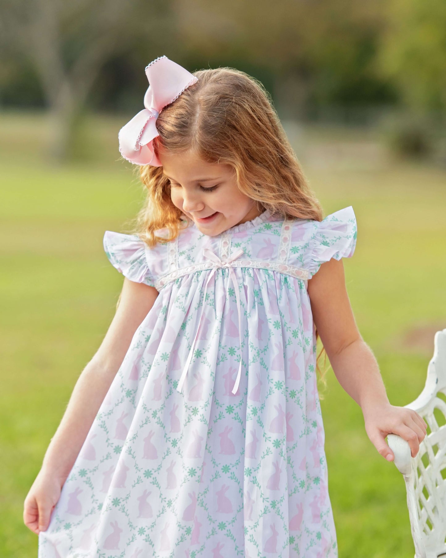 Young girl in a floral dress with a pink bow outdoors