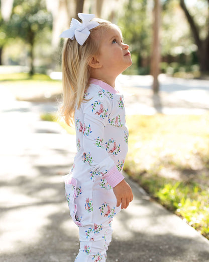 Young girl in a floral outfit standing outdoors with trees in the background