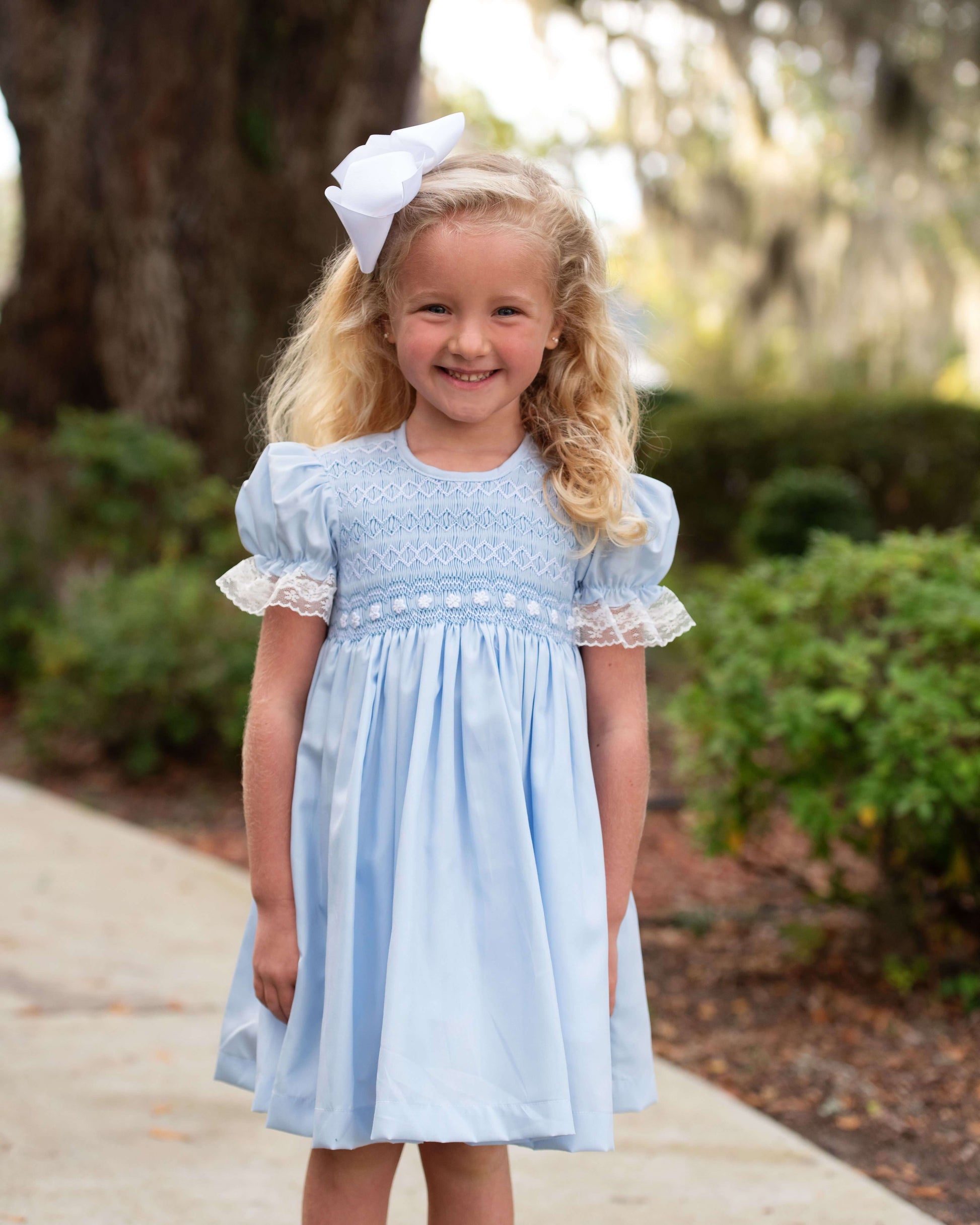 Young girl in a light blue dress with white embroidery outdoors