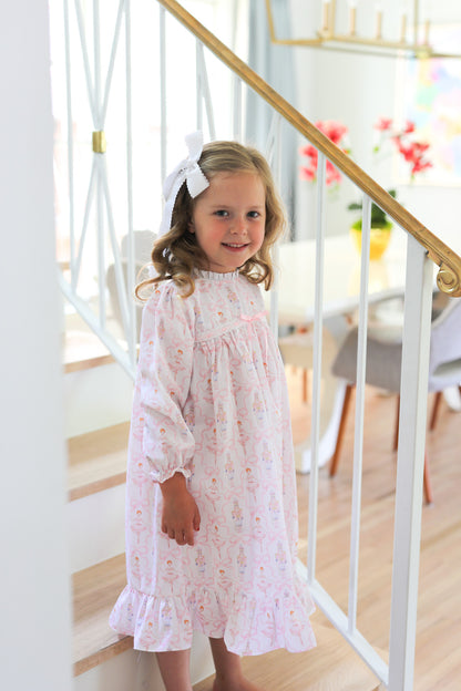 Young girl in a nutcracker ballet nightgown standing on a staircase with a blurred background
