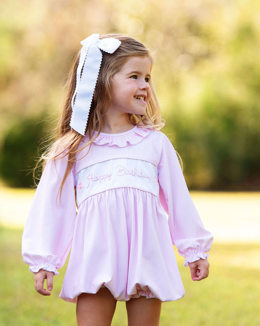 Young girl in a pink dress with a large white bow outdoors