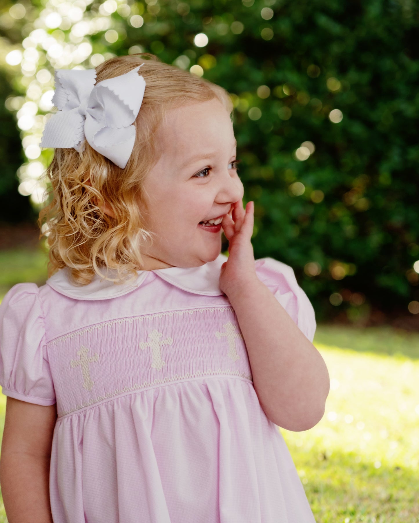 Young girl in a pink dress with a white bow outdoors