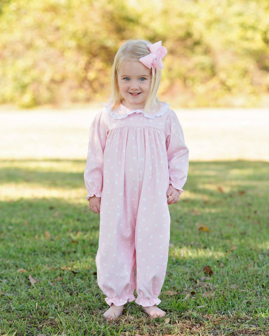 Young girl in a pink heart long bubble with a bow standing on grass