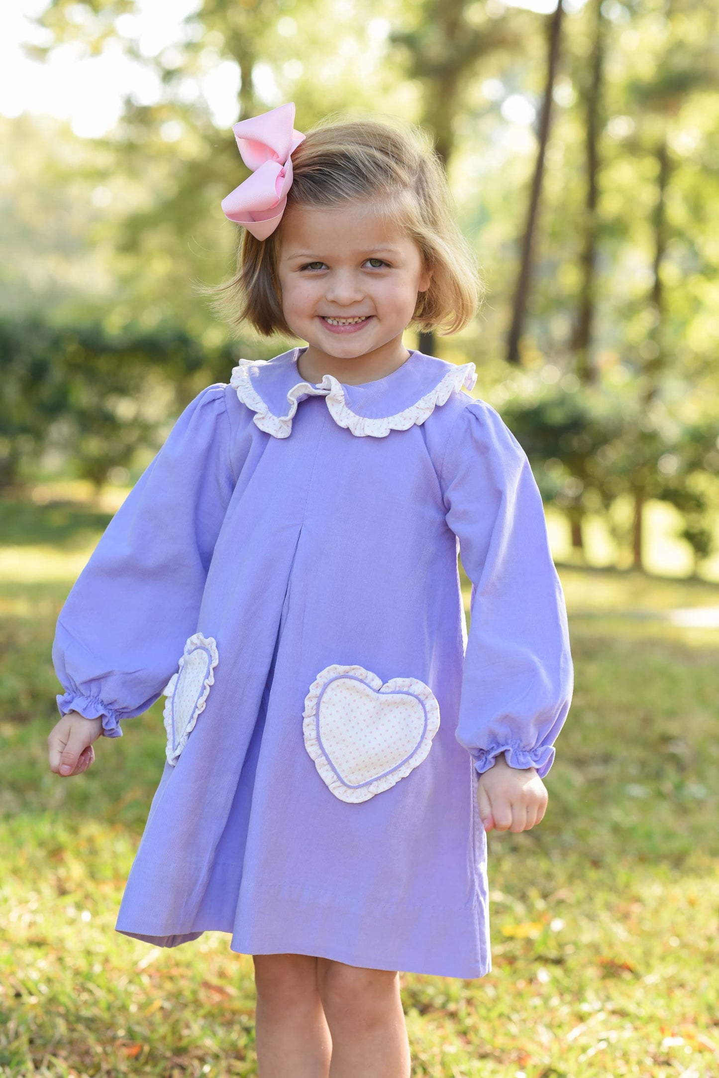 Young girl in a purple dress with white heart designs outdoors