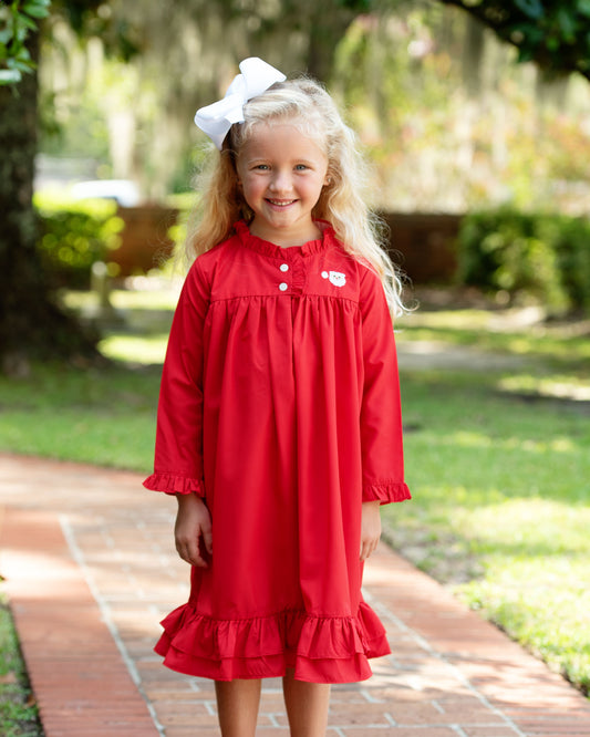 Young girl in a red dress with a white bow in a park setting