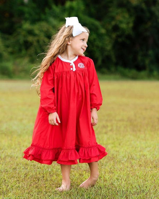 Young girl in a red night gown standing in a grassy field