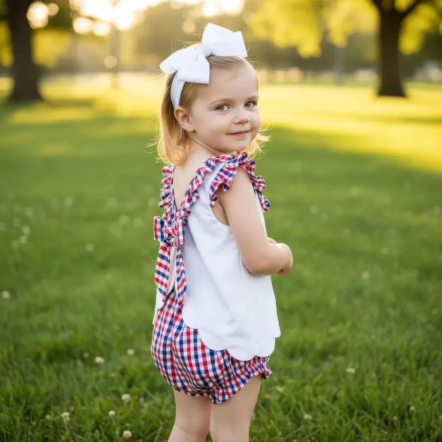 Young girl in a red, white, and blue outfit standing in a park.