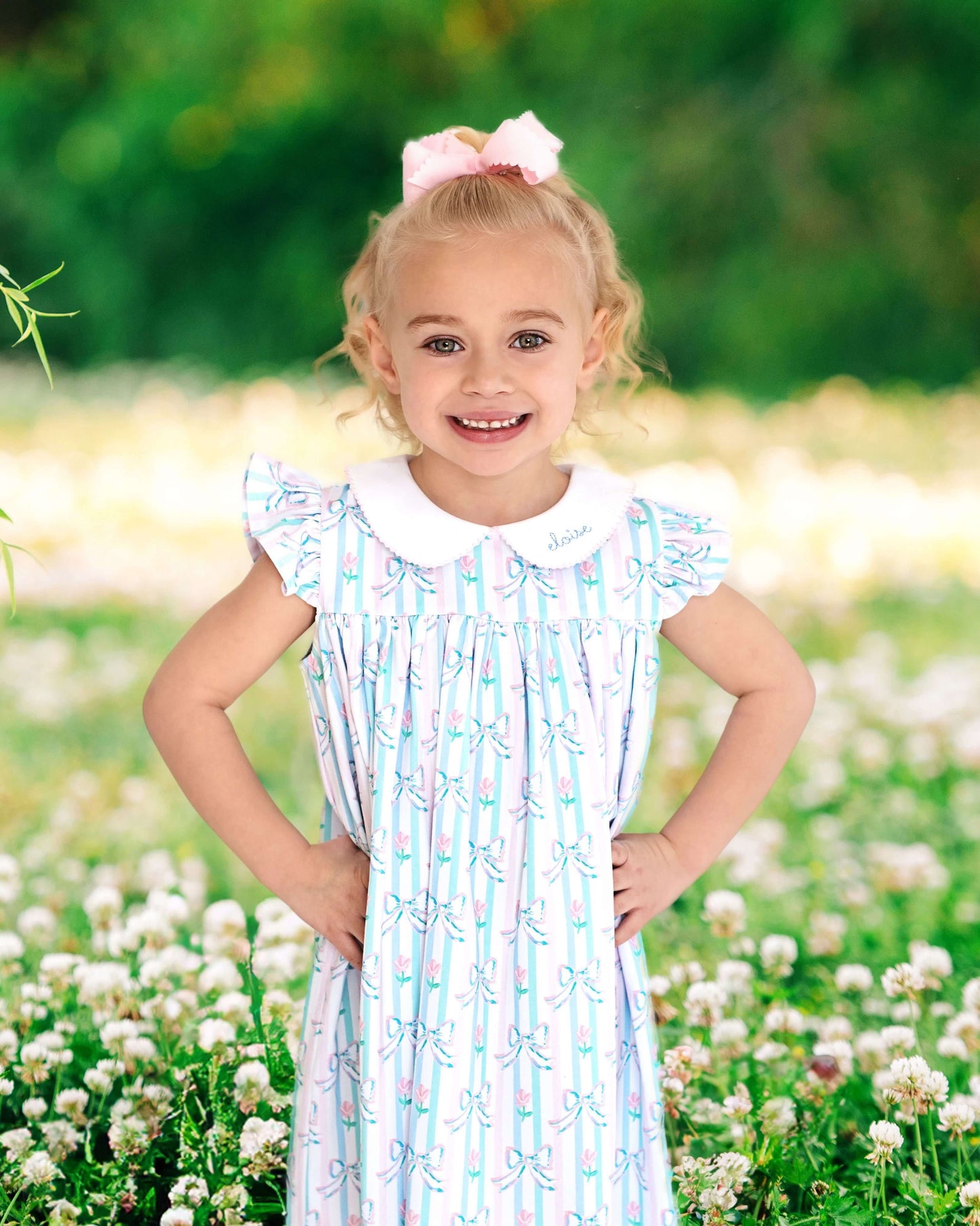 Young girl in a striped dress standing in a field of flowers with a blurred green background