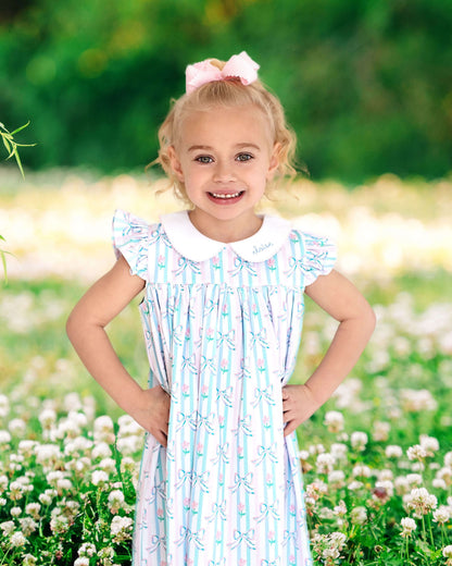 Young girl in a striped dress standing in a field of flowers with a blurred green background