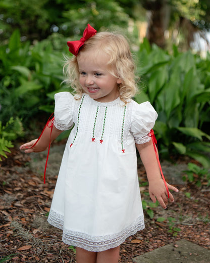 Young girl in a white dress with red ribbons and a bow outdoors