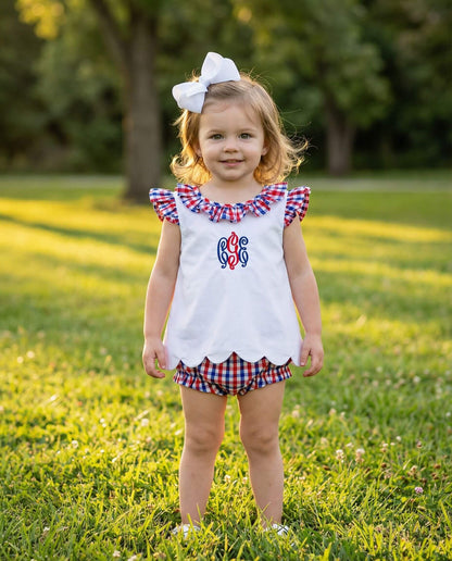 Young girl in a white outfit with red, white, and blue accents standing in a grassy field.