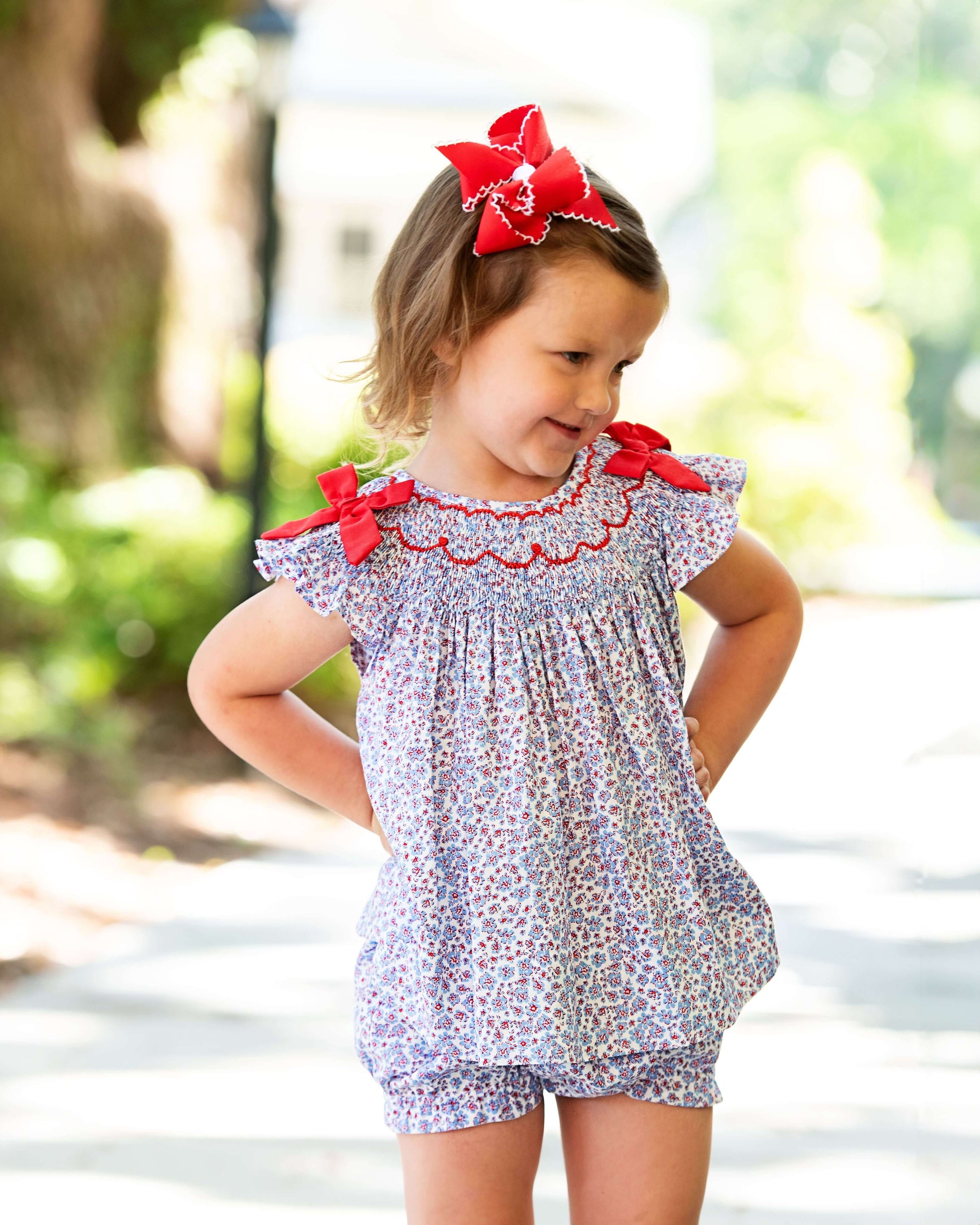 Young girl in lavender floral outfit with red bows 