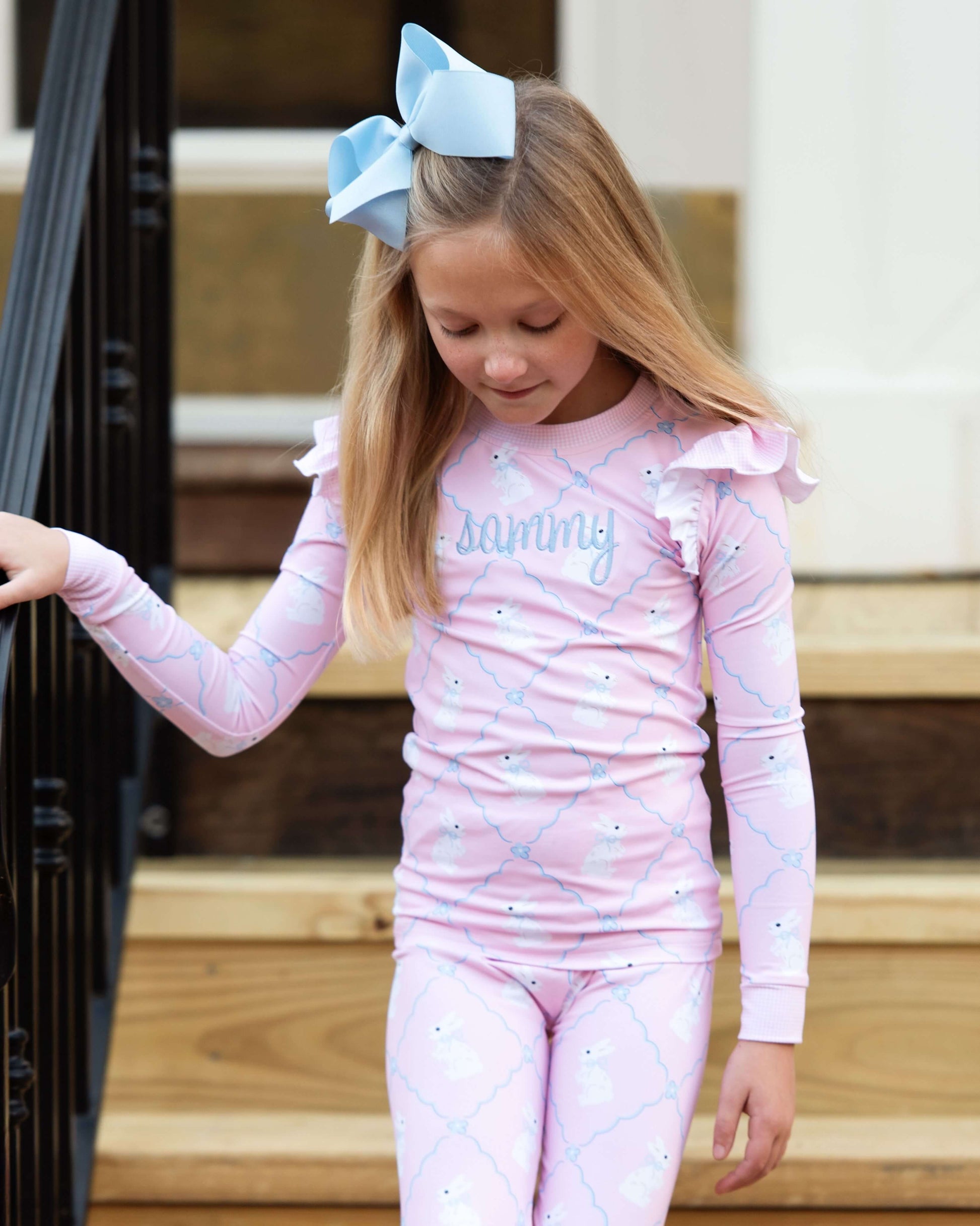 Young girl in pink pajamas with 'Sunny' on a wooden porch