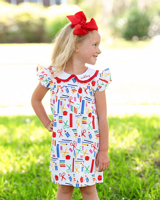 Young girl posing with hand on hip wearing a school themed dress.