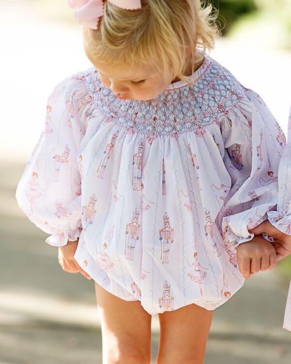 Young girl standing outside wearing a smocked nutcracker bubble