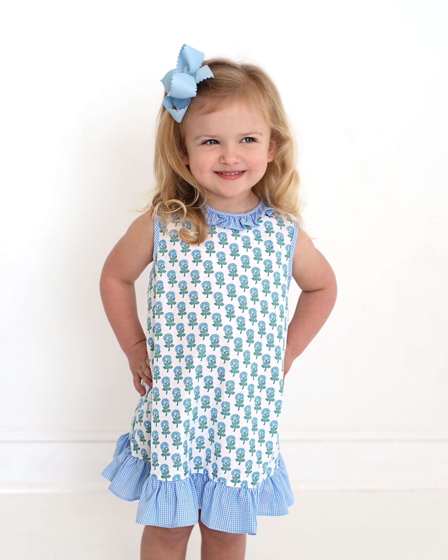 Young girl wearing a blue and white dress with a floral pattern on a white background