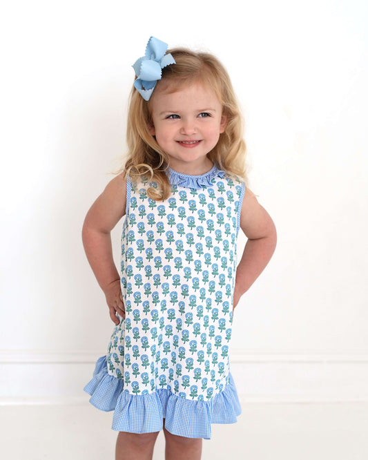 Young girl wearing a blue and white dress with a floral pattern on a white background