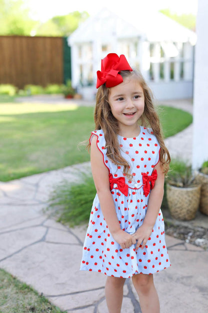 Young girl wearing a blue dress with apples on it 