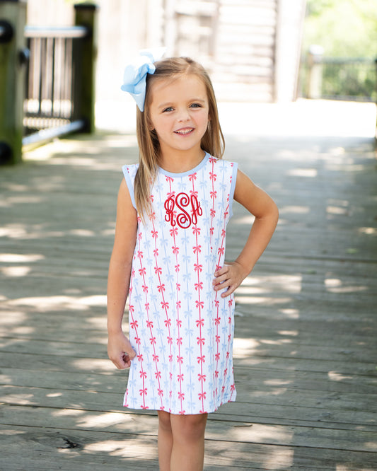 Young girl wearing a dress with a red pattern on a wooden deck