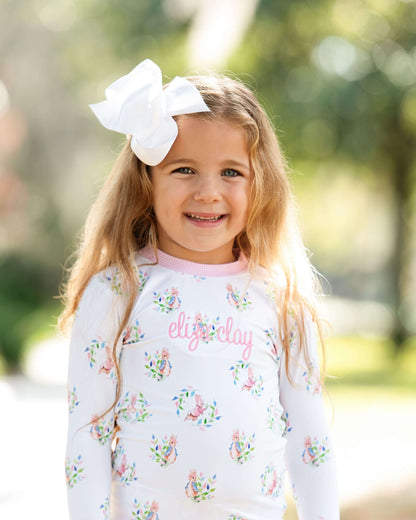 Young girl wearing a floral-patterned shirt with 'elise clay' printed on it, standing outdoors.