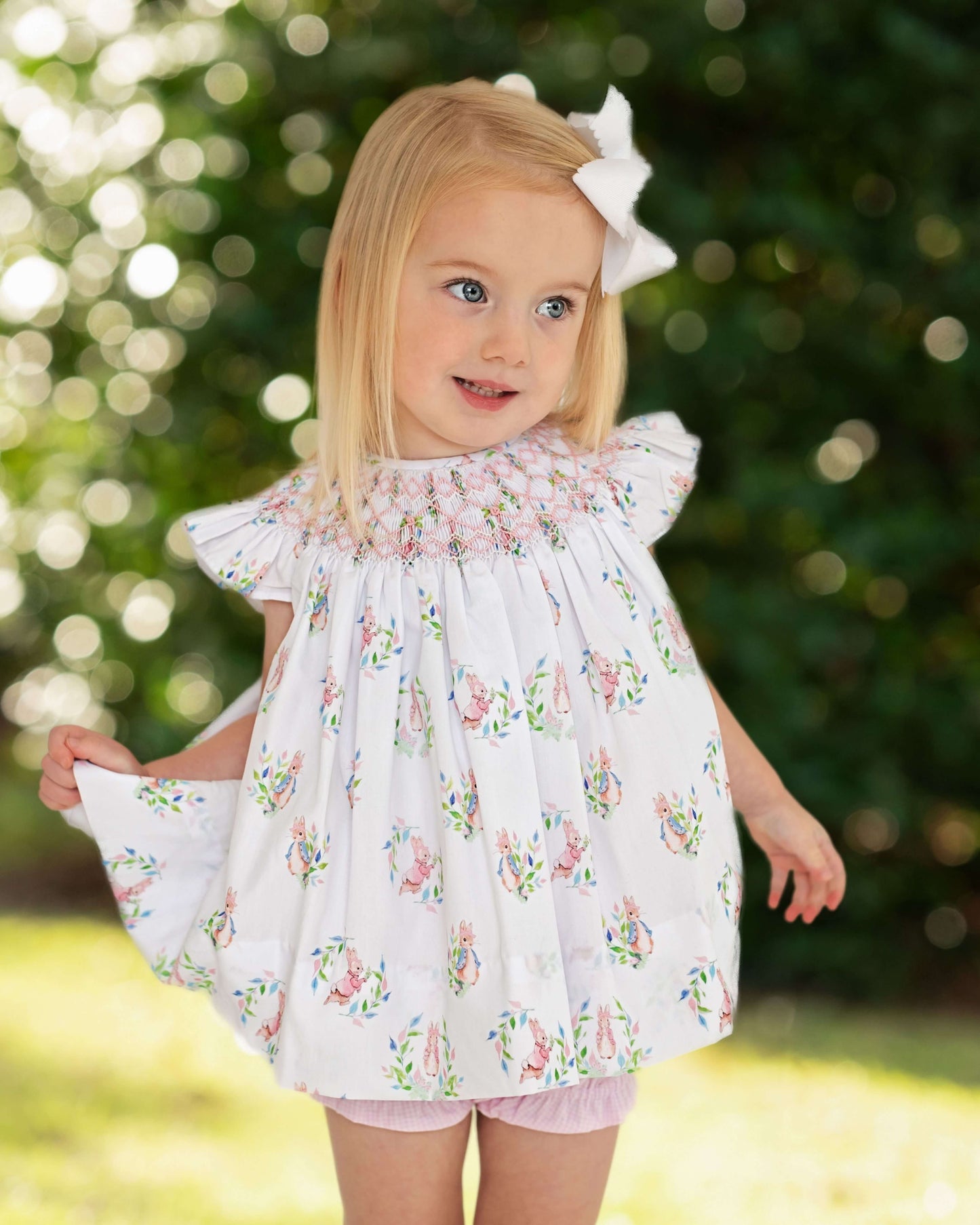 Young girl wearing a floral diaper set with a blurred green background