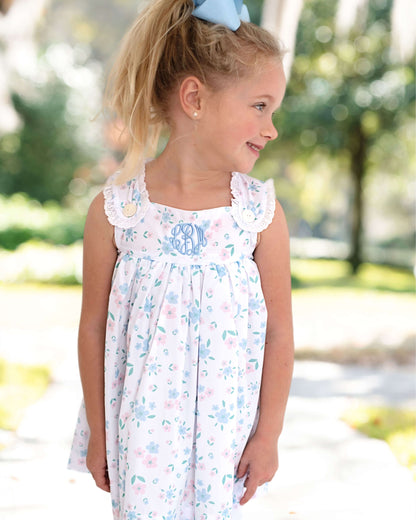 Young girl wearing a floral dress outdoors with trees in the background
