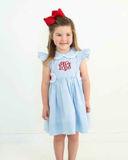 Young girl wearing a light blue dress with a red bow on a white background