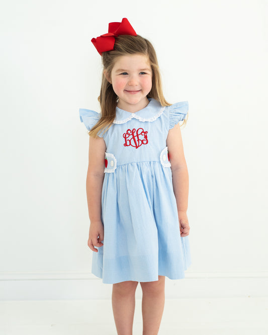 Young girl wearing a light blue dress with a red bow on a white background