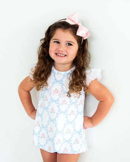 Young girl wearing a light blue dress with floral patterns against a white background
