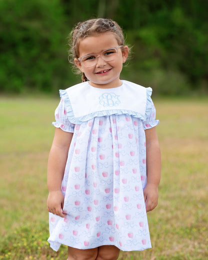 Young girl wearing a light blue dress with pink polka dots in an outdoor setting