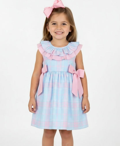Young girl wearing a light blue dress with pink ruffles and bows on a white background
