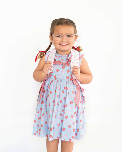 Young girl wearing a light blue dress with red patterns on a white background
