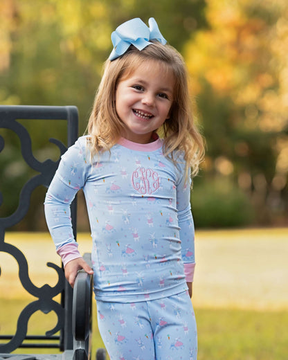 Young girl wearing a light blue outfit with pink accents, standing outdoors.