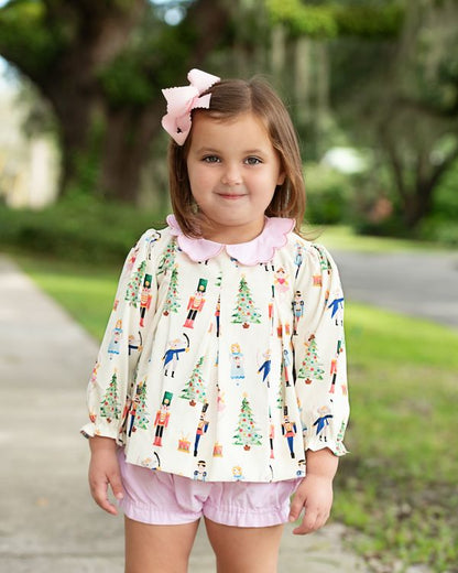 Young girl wearing a patterned blouse and pink shorts outdoors
