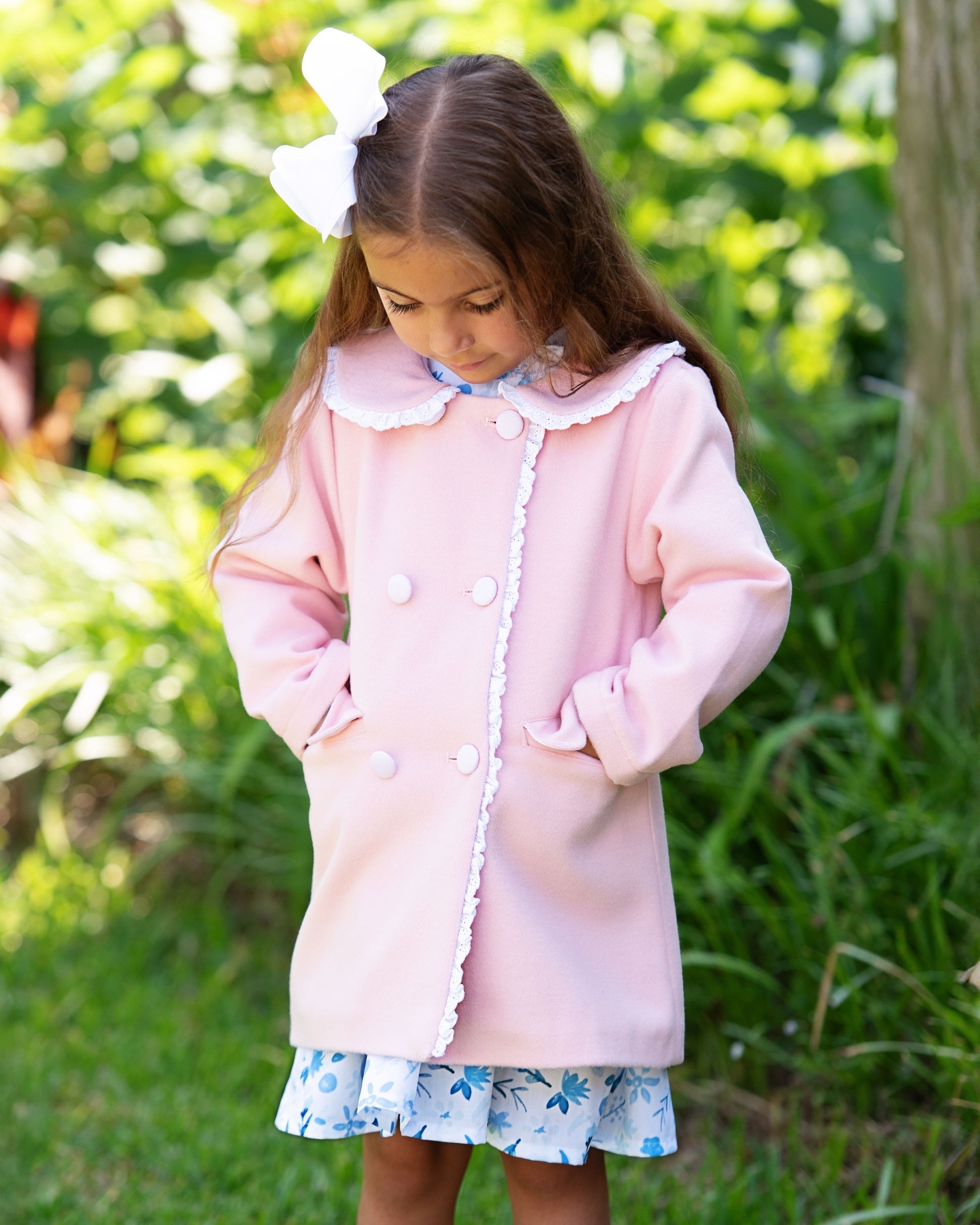 Young girl wearing a pink coat with white trim outdoors