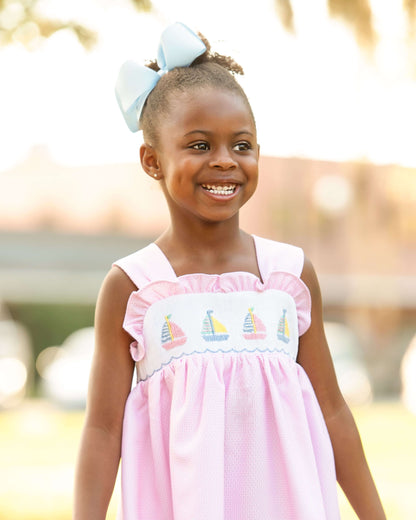 Young girl wearing a pink dress with sailboat design outdoors