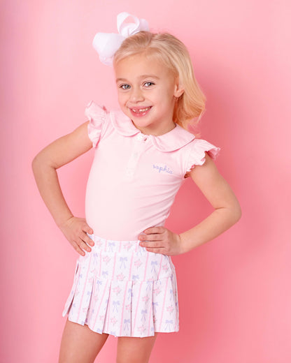 Young girl wearing a pink outfit with a white bow on a pink background