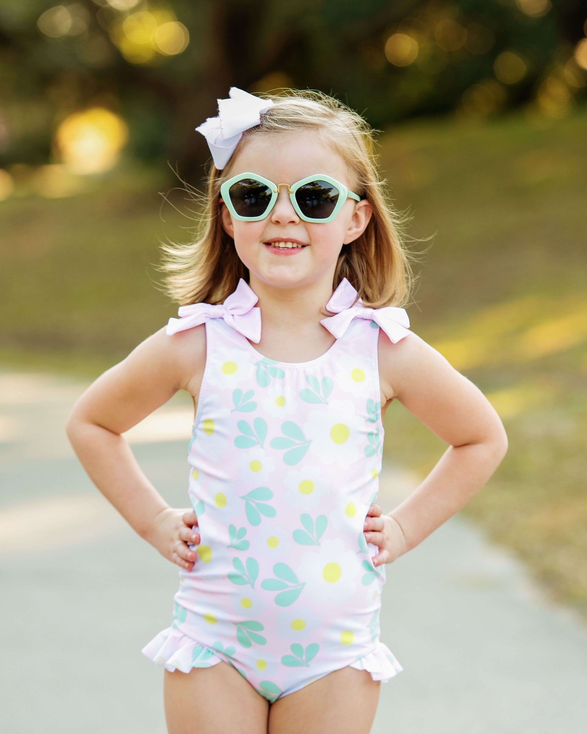 Young girl wearing a polka dot swimsuit with sunglasses outdoors